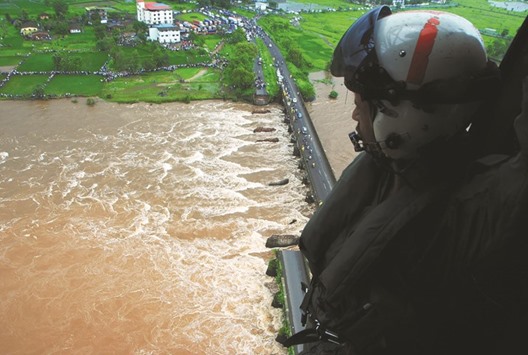 A soldier looks from a helicopter at the site of a partially collapsed bridge over the River Savitri in Raigad District of Maharashtra.