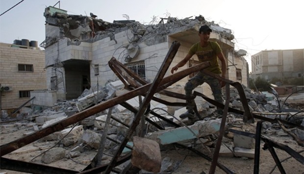 A man walks amidst debris outside the house of one of the two Palestinian gunmen