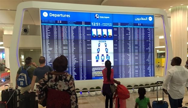 Passengers look at the departures announcement board at Dubai airport on Thursday, a day after an Emirates plane caught fire during a crash-landing.