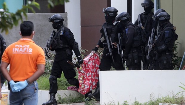 Indonesian anti-terror police carry a bag containing a suspected firearm and other evidence from a building during a raid in Batam, Riau Islands, Indonesia.