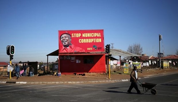 A man pushes a wheelbarrow past a billboard of the Economic Freedom Fighters (EFF), which is led by Julius Malema, President Jacob Zuma's one-time protege and a former ANC youth leader, in Soweto on Friday.
