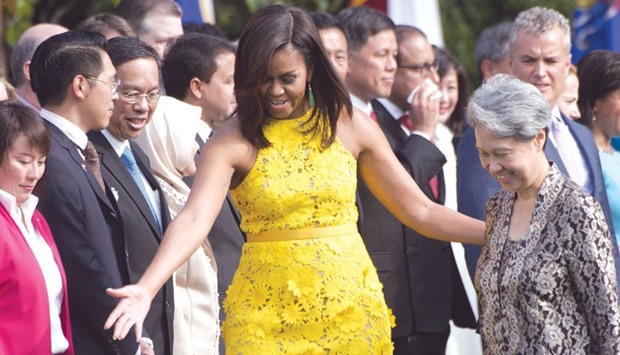 This file photo taken on August 2 shows US First Lady Michelle Obama with Ho Ching, wife of Singaporeu2019s Prime Minister Lee Hsien Loong, for a ceremony on the South Lawn of the White House in Washington, DC. A dinosaur print purse designed by an autistic teenage boy has completely sold out after photographs of Ho bearing it at the White House went viral.