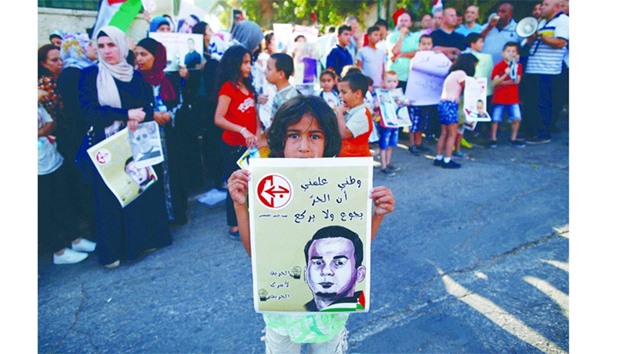 A Palestinian girl holds a poster with a picture of Bilal Kayed, during a demonstration against his detention by the Israeli authorities, near the Red Cross offices in East Jerusalem on August 3, 2016.