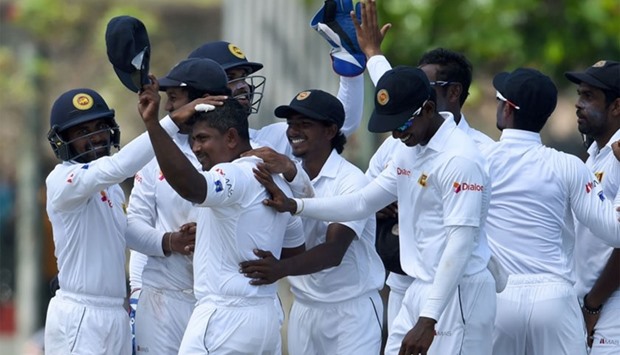 Sri Lanka's cricketer Rangana Herath (2L) celebrates with his teammates after he took the hat-trick wicket of Australian batsman Mitchell Starc during the second day of the second Test cricket match between Sri Lanka and Australia at The Galle International Cricket Stadium in Galle on August 5, 2016.