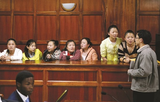 Taiwanese and Chinese nationals, arrested on suspicion of involvement in telecommunications fraud, listen to their translator as they sit inside the Milimani Law Courts in Nairobi, before they were acquitted of cyber crime.