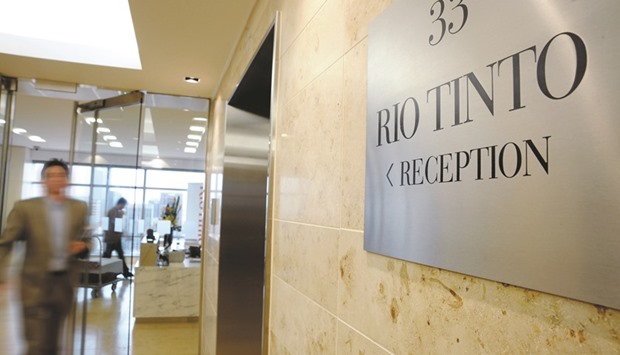 A man walks through the entrance from the reception area of Rio Tintou2019s head office in Melbourne. The company has to work twice as hard to turn the profit it did a decade ago.