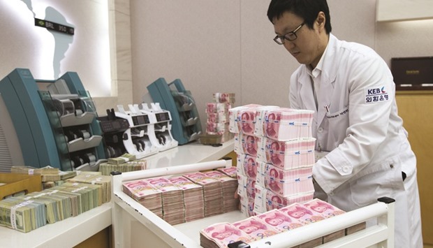 An employee arranges Chinese yuan banknotes at the Korea Exchange Bank headquarters in Seoul. A gauge of swings in the yuan fell to the lowest level since November amid receding bearish bets and speculation Chinau2019s central bank is helping keep the exchange rate stable.