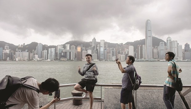 PICTURE TIME:  People pose for photos and take selfies on a promenade overlooking Victoria Harbour in Hong Kong on August 2, 2016, as storm clouds pass during a u201cT8u201d storm signal raised for Typhoon Nida. Hong Kong shut down on August 2 as Typhoon Nida brought violent winds and torrential rain, with hundreds of flights cancelled and the stock market, schools and businesses closed, as the storm headed across southern China. Photo by AFP