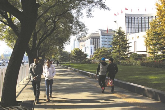 Pedestrians walk past the Peopleu2019s Bank of China headquarters (right) in the financial district of Beijing. Net foreign exchange sales by the PBoC in June jumped to their highest in three months, as the central bank sought to shield the yuan from market volatility caused by Britainu2019s decision to leave the European Union.