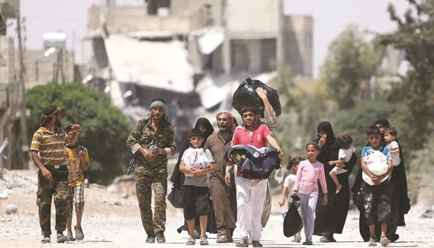 Syria Democratic Forces (SDF) fighters walk with people that fled their homes due to clashes between Islamic State fighters and SDF towards safer parts of Manbij, in Aleppo Governorate, Syria, yesterday.