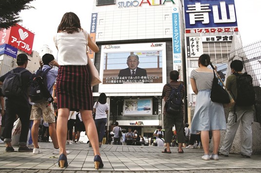 People watch Emperor Akihitou2019s video address on a large screen in Tokyo.