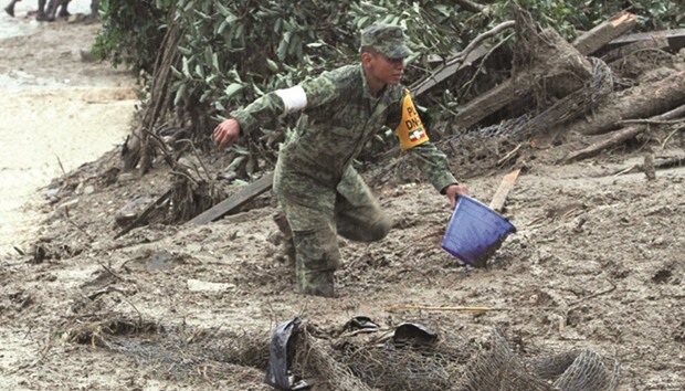 A Mexican soldier helps dig out damaged homes in the community of Tlaola, Puebla in eastern Mexico in the wake of Tropical Storm Earl.
