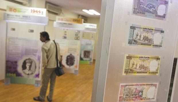 A man walks past rupee notes displayed in an exhibition of the Reserve Bank of India. Risks to the rupee could stem from a change in the central banku2019s policies, particularly on foreign-exchange management, as investors await the announcement of RBI governoru2019s successor.