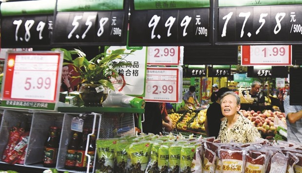 A woman looks at boards showing prices at a supermarket in Hangzhou, Zhejiang province. The producer price index in China, which measures the cost of goods at the factory gate, fell 1.7% year-on-year last month, the National Bureau of Statistics said yesterday.