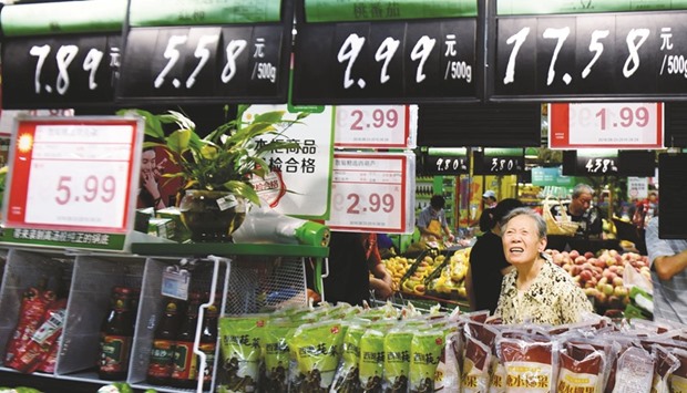 A woman looks at boards showing prices at a supermarket in Hangzhou, Zhejiang province. The producer price index in China, which measures the cost of goods at the factory gate, fell 1.7% year-on-year last month, the National Bureau of Statistics said yesterday.