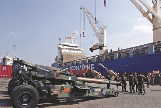 Workers unload a Humvee, as Lebanese Army soldiers stand near Howitzers, part of a military donation from the US government to the Lebanese army, during a ceremony at Beirutu2019s port, yesterday.