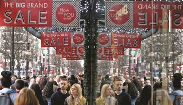 Shoppers are reflected in a store window as they pass sales advertisements on Oxford Street in London. According to the British Retail Consortium, retail spending in July was 1.9% higher than a year earlier, the biggest rise in six months and up sharply from 0.2% growth in June, when bad weather added to uncertainty around the Brexit vote.