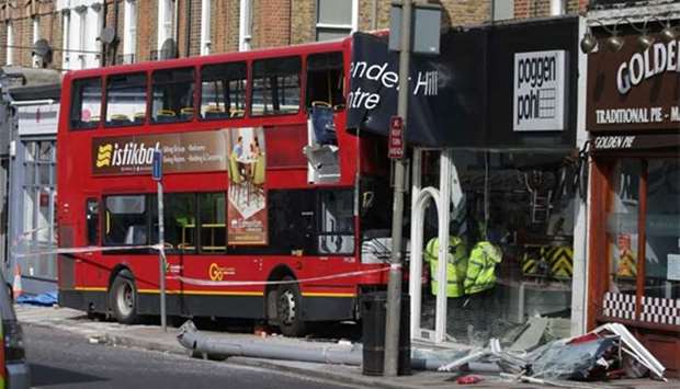 Emergency workers examine the scene of an accident where a London bus ploughed into a shop on a busy street in southwest London on Thursday.