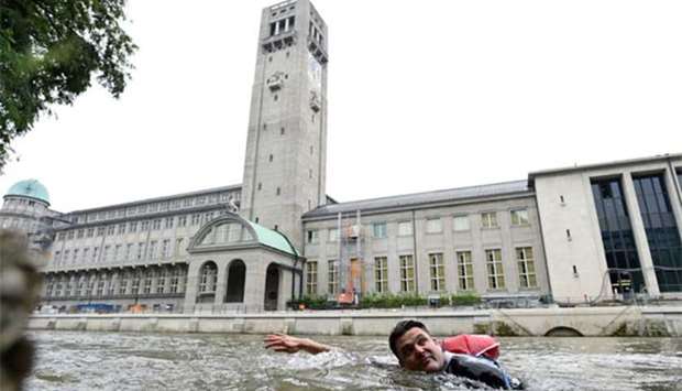 Benjamin David passes the Deutsches Museum as he swims from his home to his workplace along the River Isar in Munich on Thursday.