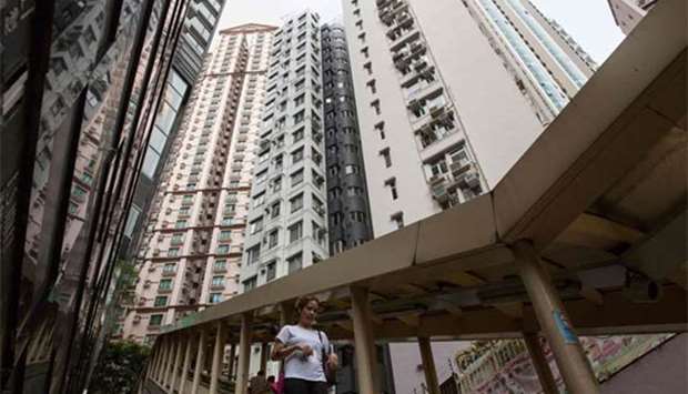 A woman walks down a path, as high-rise residential buildings installed with air conditioning units are seen in the background, in Hong Kong's Mid-Levels district on Friday.