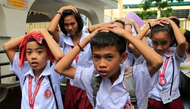 Students use their hands to cover their heads as they evacuate their school premises after an earthquake hit the northern Philippine island of Luzon and was felt in the Metro Manila on Friday.