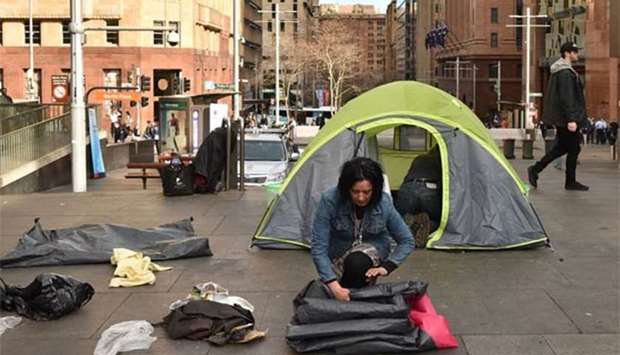 A homeless woman packs up her belongings in Martin Place, which has become known as ,Tent City,, in the central business district of Sydney on Friday.