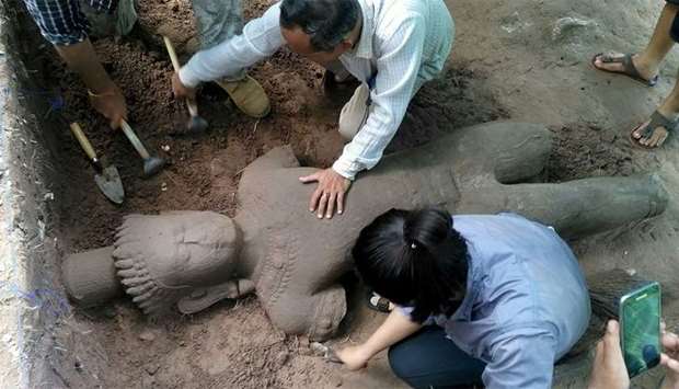 Archaeologists excavating a statue from the ground at the complex in Siem Reap province