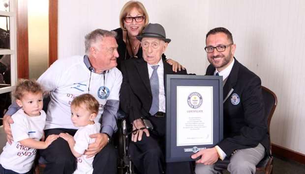Marco Frigatti (R), Head of Records for Guinness World Records, presenting Israel Kristal (2nd-R) with his certificate of achievement for Oldest Living man, in the presence of the Kristal's daughter (top, son (L) and grandchildren. A picture released by Guinness World Records on March 11, 2016.