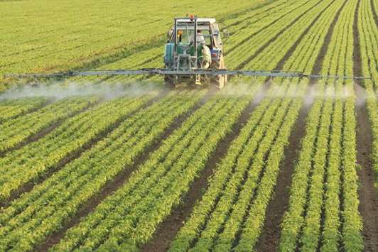 Farming tractor spraying a field.