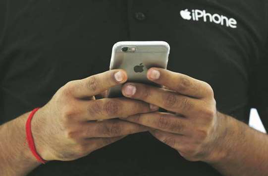 A salesman uses his iPhone at a mobile phone store in New Delhi. The US tech giant has been in talks with Indian officials since May of last year, when CEO Tim Cook and Prime Minister Narendra Modi agreed to set up a production base in India that goes beyond just assembling the devices, as happens today.