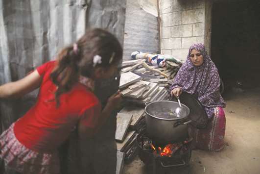 A Palestinian woman cooks on a wood fire at her house during power cut in Beit Lahiya town in the northern Gaza Strip July 6, 2017.