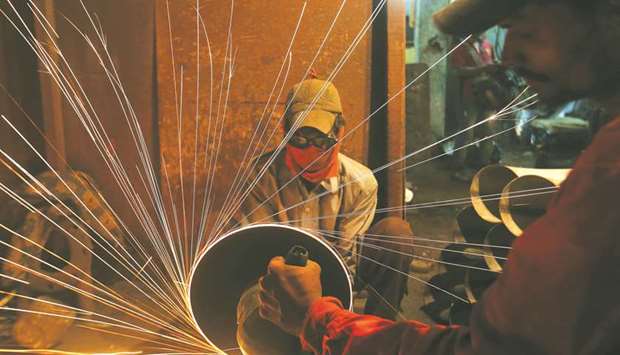 A worker cuts metal inside a workshop manufacturing pipes in Mumbai. In its mid-year economic survey, the finance ministry said u201ctighteru201d monetary policy meant real interest rates in India were substantially higher than in comparable emerging economies, further clouding the economic outlook.