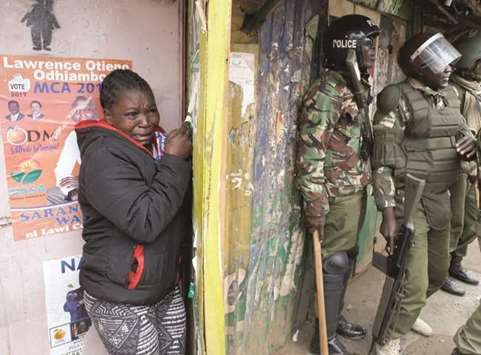A woman cries as she stands behind police officers during clashes between Odinga  supporters and the police, in Nairobiu2019s Kibera slum.