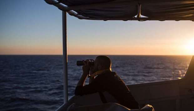 A member of ,SOS Mediterranee,, a European association dedicated to search and rescue, uses binoculars during a search operation on the Mediterranean sea, 30 nautical miles from the Libyan coast, on July 31