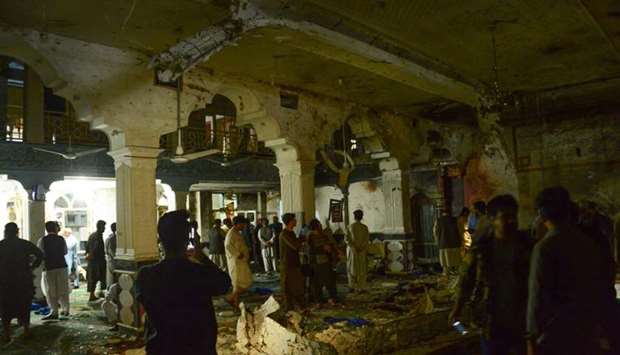:Afghan security personel inspect the site of a suicide bomb attack at a Shiite mosque in Herat