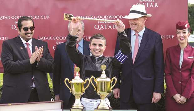 Qatar Racing and Equestrian Club general manager Nasser Sherida al-Kaabi (left) applauds as jockey Andrea Atzeni (centre) lifts the trophy after guiding Stradivarius to Qatar Goodwood Cup victory at the Qatar Goodwood Festival yesterday. PICTURE: Juhaim