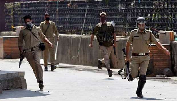Indian police officers chase protesters in Srinagar this week.