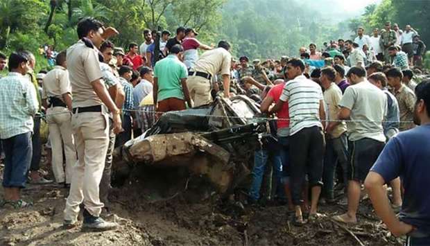Police and local residents search a vehicle for survivors following a landslide that swept away a highway in Himachal Pradesh.