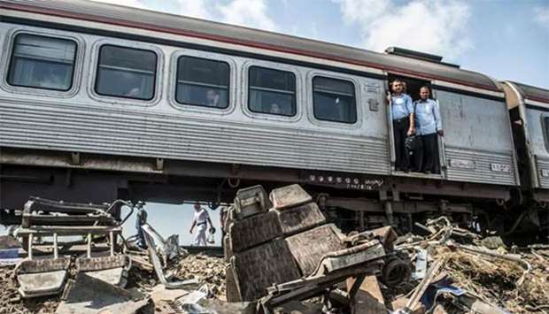 Passengers on a train, which slowed down at the scene of a fatal rail collision, look at the wreckage at Khorshid, on the outskirts of Alexandria.