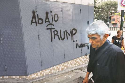 A man walks past graffiti in Caracas reading u2018Down with Trump ... Rotu2019.