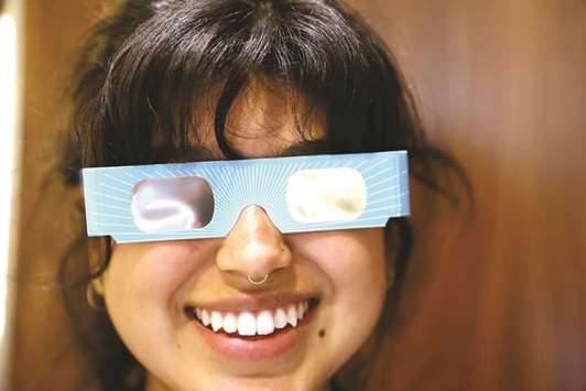 Warby Parker employee Karolyna Landin poses with a pair of solar eclipse glasses that the eyeglass store is giving out for free in New York City.