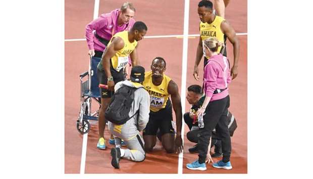 Jamaicau2019s Usain Bolt (centre) grimaces in pain as teammates and medical staff try to help him during the menu2019s 4x100m relay final at the 2017 IAAF World Championships in London on Saturday. (AFP)