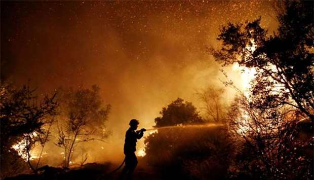 A firefighter tries to extinguish a wildfire burning near the village of Kalamos, north of Athens, on Sunday.