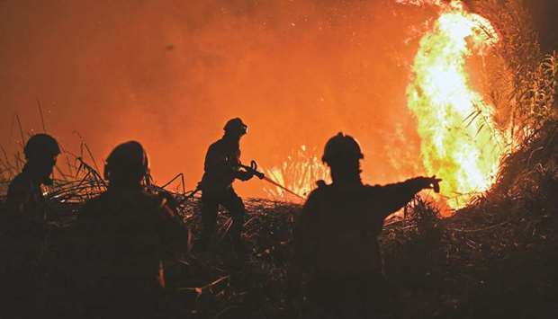 Firefighters try to extinguish a wildfire following a new rash of forest fires ahead of a weekend of warm temperatures, at Rio de Moinhos village in Abrantes, Portugal.