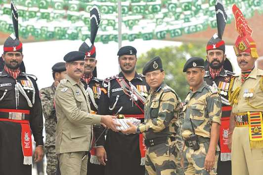 Pakistani Wing Commander Bilal (second left) presents sweets to Indian Border Security Force (BSF) Commandant Sudeep (fourth right) during a ceremony to celebrate Pakistanu2019s Independence Day at the India-Pakistan Wagah border post yesterday.