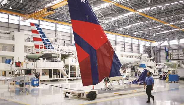 Employees walk past a vertical stabiliser with a livery for Delta Air Lines on the production floor of the Airbus Final Assembly Line facility in Mobile, Alabama. Delta is the first major US carrier to buy the C Series, a midrange aircraft that offers roomier interiors than regional jets while typically carrying fewer passengers than a plane from the Boeing 737 or Airbus A320 families.
