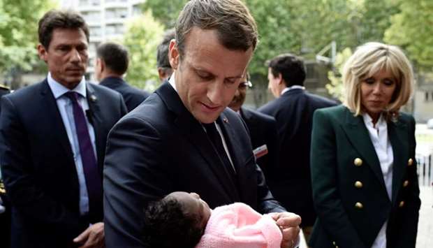 French President Emmanuel Macron (C), flanked by his wife Brigitte Macron (R), holds a baby as he visits the Robert-Debre pediatric hospital in Paris, France, August 9, 2017