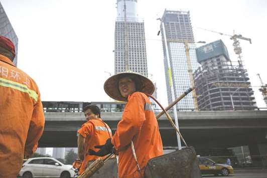 A group of cleaners prepare to cross a street in the central business district in Beijing. The International Monetary Fund expects Chinau2019s economy to grow 6.7% this year, above the governmentu2019s target of about 6.5%.