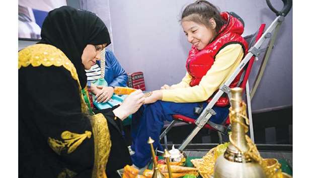 A child receives henna decoration with great joy.