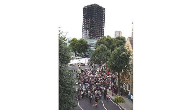 People take part in a silent march in memory of the victims of the Grenfell Tower fire in front of the burned-out shell of the building in west London on Monday. The march marked two months since the June 14 fire, which spread ferociously through the 24-storey west London block and killed at least 80 people.